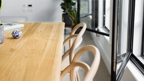 Une table de salle à manger en bois, avec des chaises, un vase et un livre.