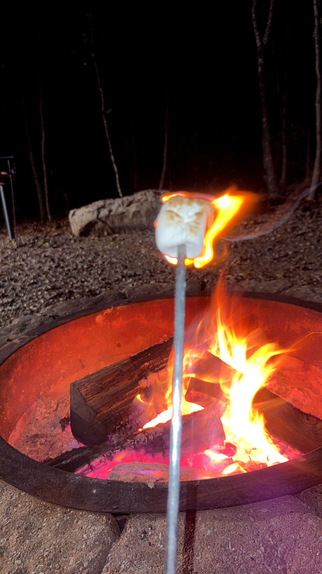 Een kampvuur met een marshmallow aan een stok.