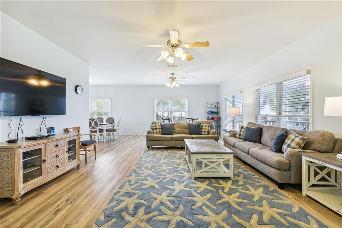 A living room with a large flat-screen TV, two sofas, a coffee table, and a patterned rug.