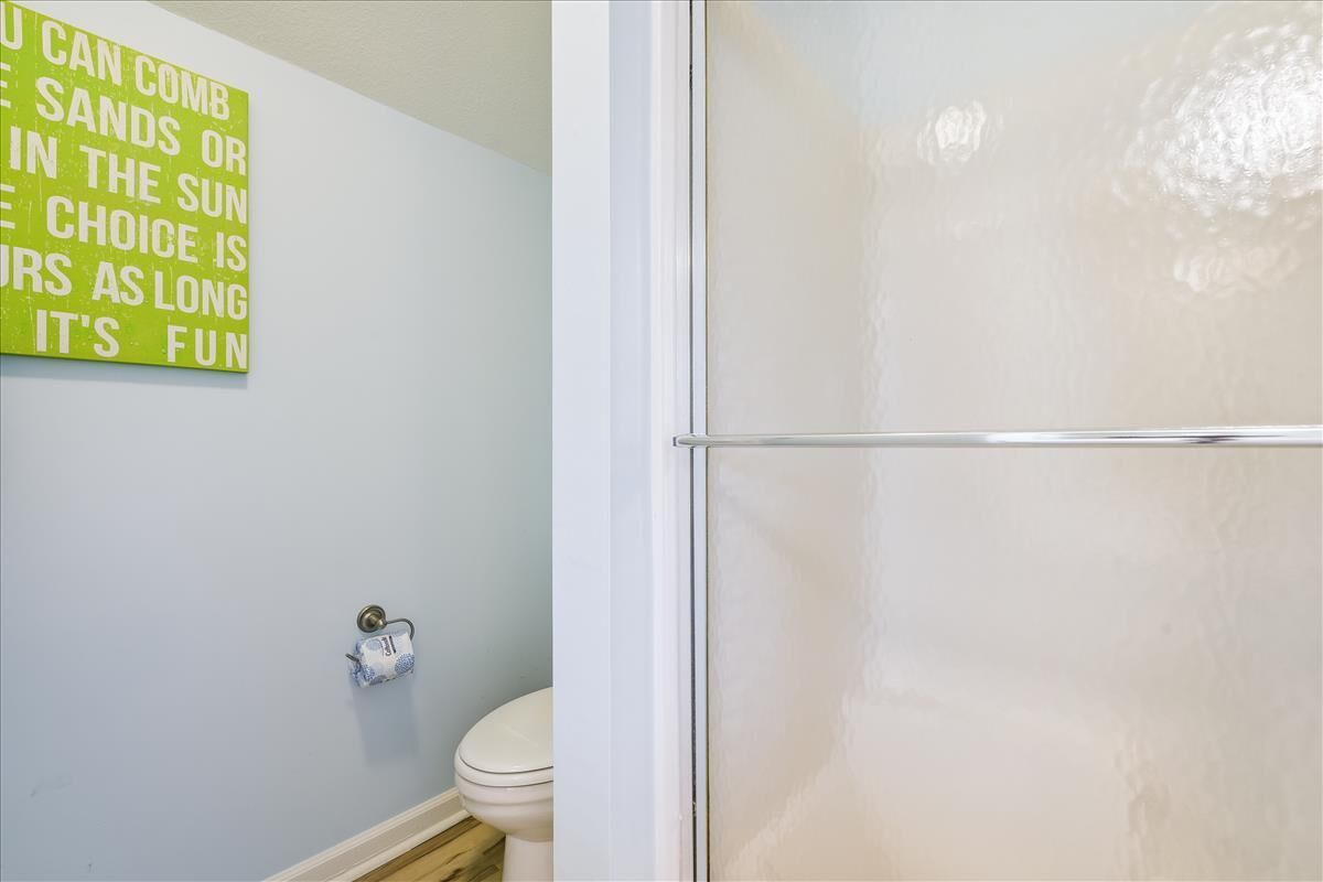A bathroom with a toilet, a towel rack, and a shower enclosure.