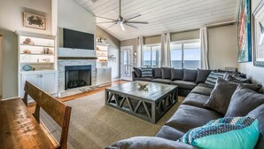 A spacious living room with a fireplace, a large sectional sofa, a coffee table, and a ceiling fan. - Coastal Cottage is situated on the island's east end near the State Park. (St. George Island)