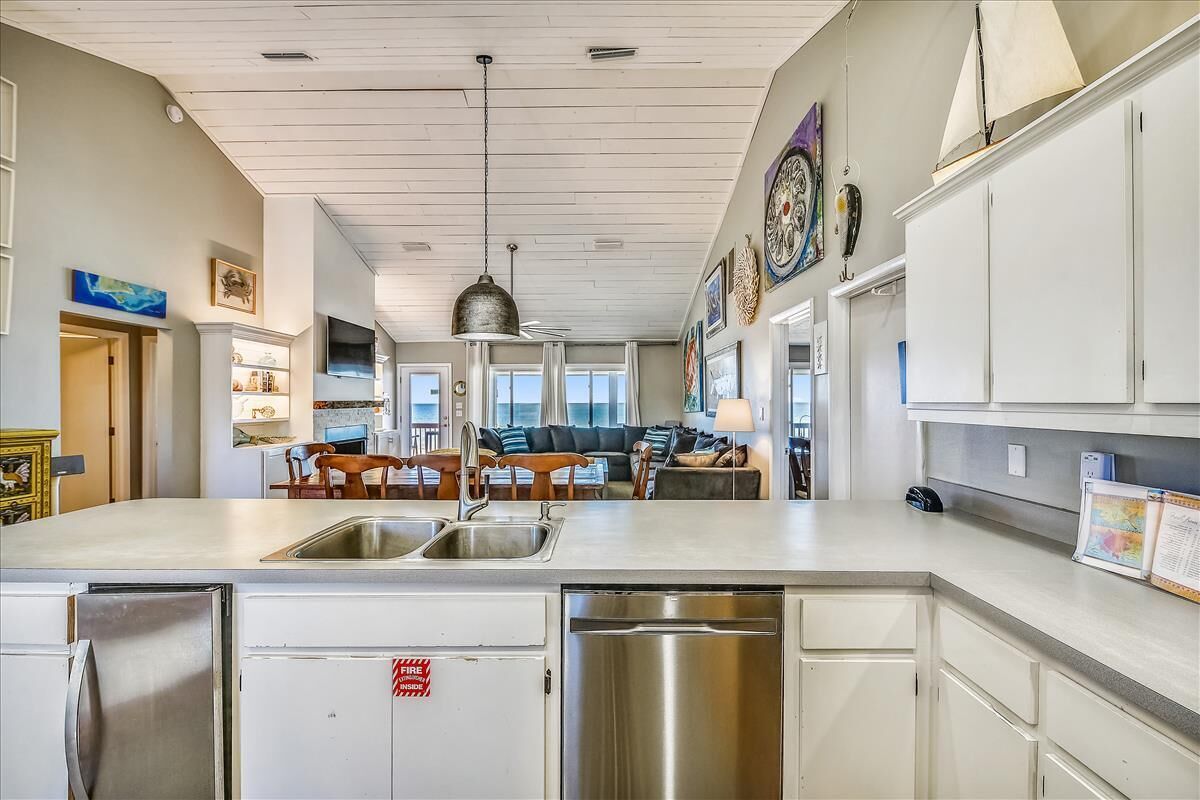 A modern kitchen with white cabinetry, stainless steel appliances, and a central island with a sink.