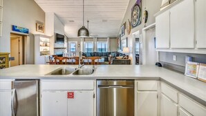 A modern kitchen with white cabinetry, stainless steel appliances, and a central island with a sink. - Coastal Cottage is situated on the island's east end near the State Park. (St. George Island)