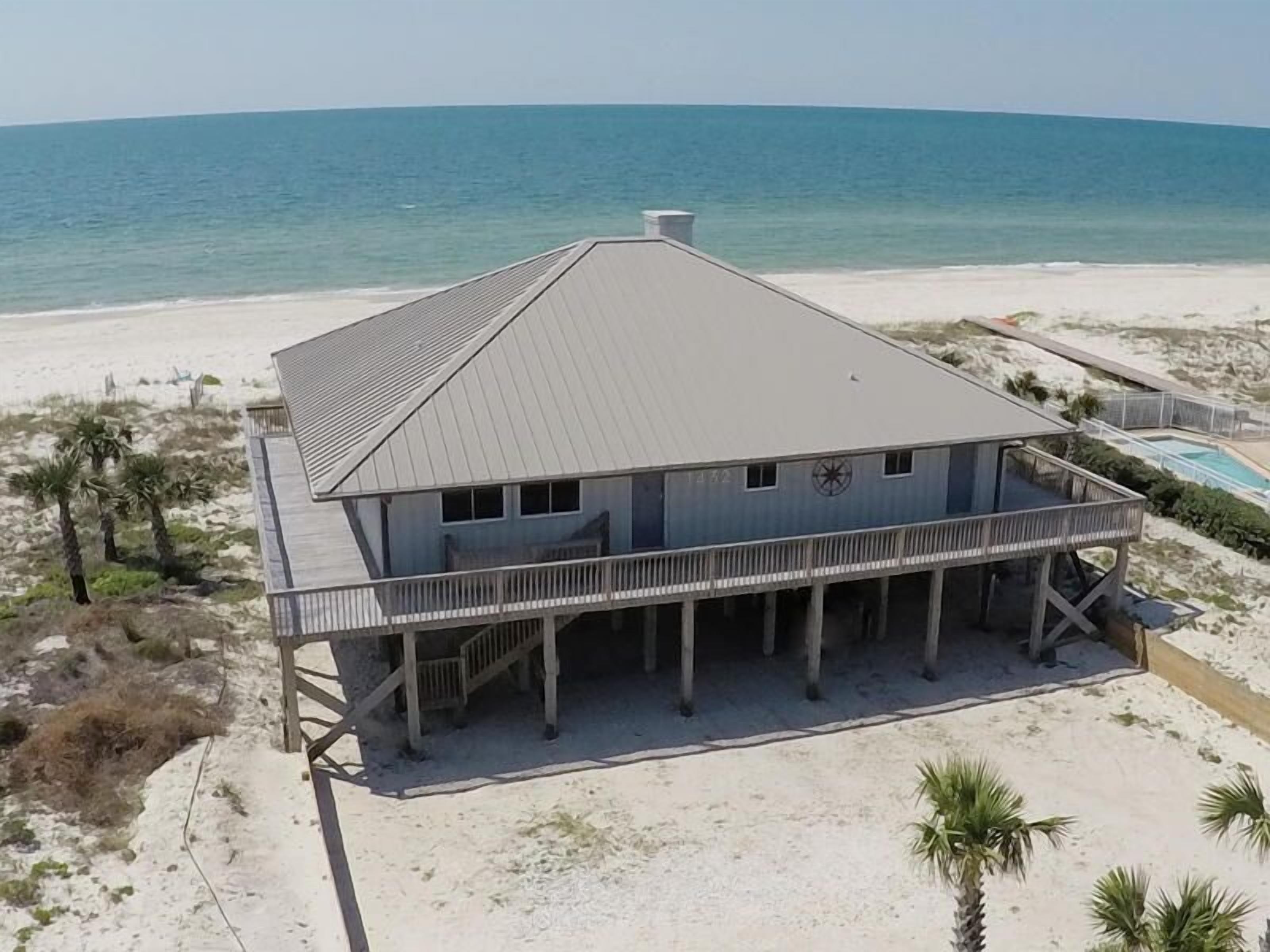 Una casa frente a la playa con un balcón grande, piscina y vistas al océano.
