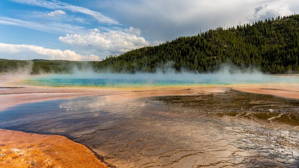 A geothermal area with mineral deposits and a forested hillside. - Homestead 1: Cozy 2BR in West Yellowstone, just 1 minute from Yellowstone Park! (West Yellowstone)