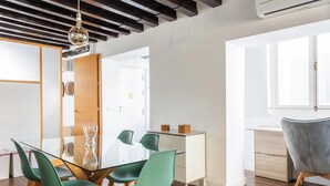 Zona pranzo moderna con tavolo in vetro, sedie verdi e soffitto in legno.