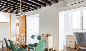 A modern dining area with a glass table, green chairs, and a grey upholstered chair.