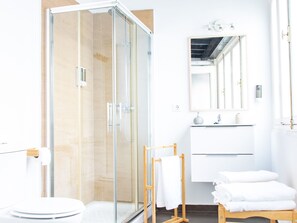 Ein modernes Badezimmer mit einer Duschkabine, einer Toilette, einem Waschbecken und einem Spiegel.