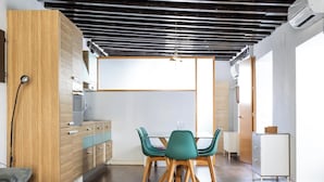 Una cucina moderna con mobili in legno, un'area pranzo con sedie color petrolio e un pavimento in legno.