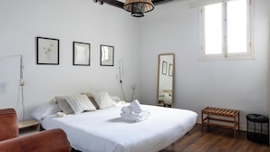 Una camera da letto con un letto, un comodino, una sedia, una panca in legno e una finestra.