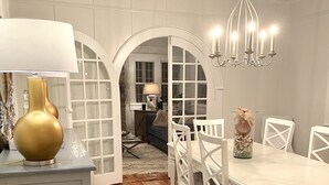 Un coin repas avec une table et des chaises blanches, un lustre et un tapis.