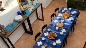 A dining area with a long table set for a meal, a mirror, and a bookshelf. - Dar Lola, guest house in the medina (Houmt Souk)