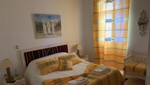 A neatly arranged bedroom with a bed, bedside table, lamp, and a chair. - Dar Lola, guest house in the medina (Houmt Souk)