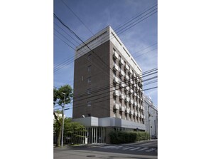 Stylish building with a symmetrical facade and balconies on each floor, featuring a glass entrance.