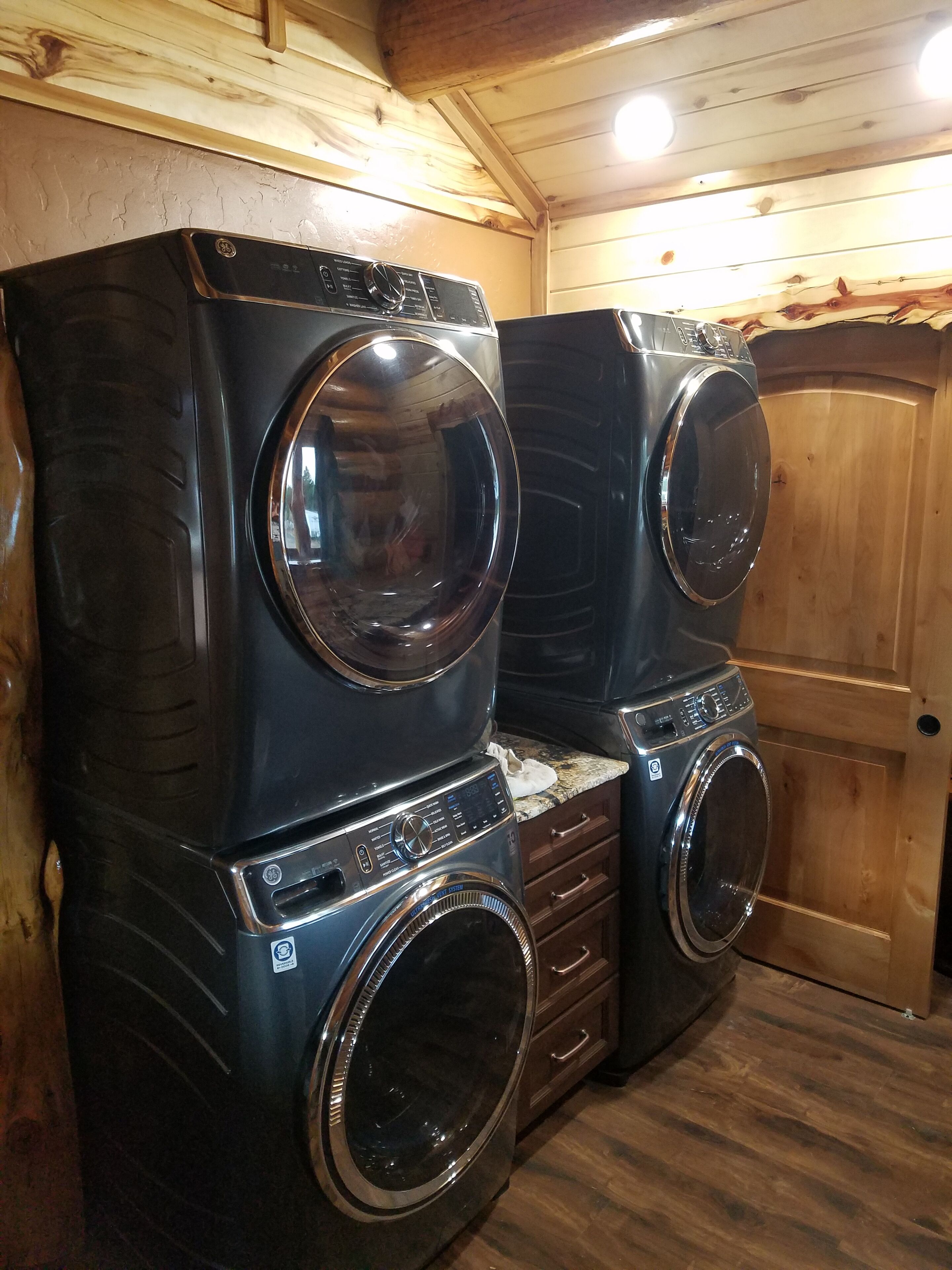 Un lavadero con dos lavadoras de carga frontal apiladas y una puerta de madera.