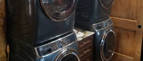 Un lavadero con dos lavadoras de carga frontal apiladas y una puerta de madera.