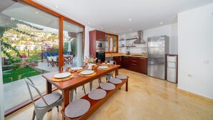 A modern kitchen with a large island, stainless steel appliances, and a view of a hillside.