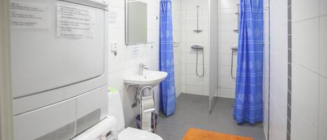 A bathroom with a washing machine, a sink, a toilet, and a shower area with blue curtains.