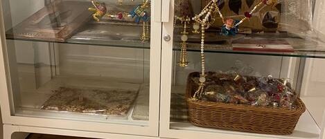 A glass-fronted cabinet with multiple shelves, some containing decorative items and others empty.