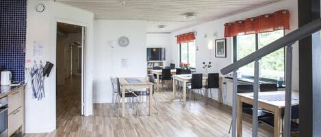 Una cocina amplia con pisos de madera, un comedor con mesas y sillas, y una escalera que lleva a otro nivel.