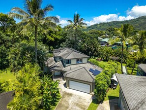 Ein Wohnhaus mit Garage, Solaranlage und üppiger tropischer Bepflanzung.