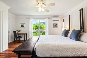 Ein Schlafzimmer mit einem Bett, einem Schreibtisch und Blick auf Grünfläche.