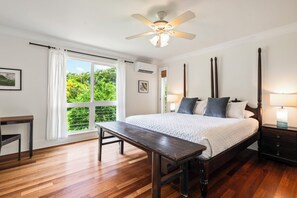 A bedroom with a bed, a bench, a nightstand, a lamp, and a ceiling fan.