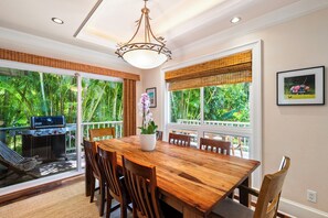 An indoor dining area with a wooden table, chairs, and a hanging light fixture.