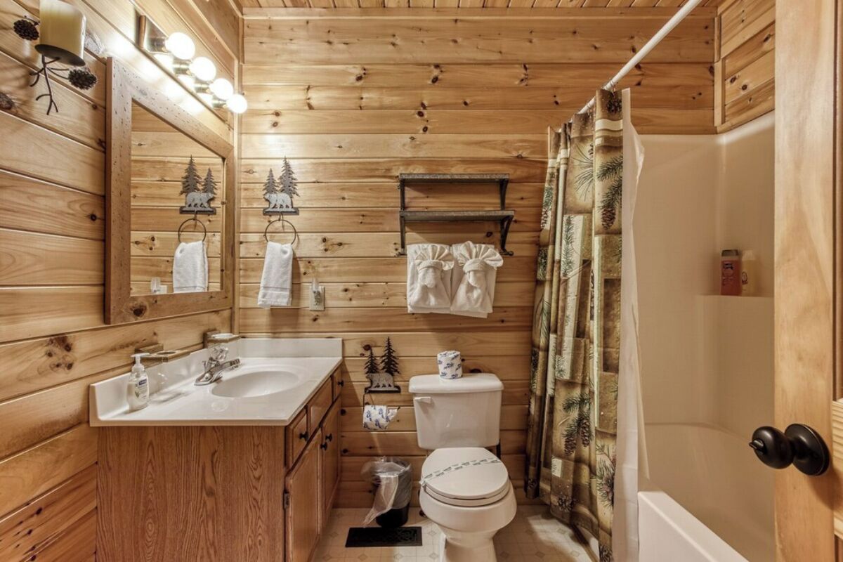 A wooden cabin bathroom with a sink, toilet, and shower.