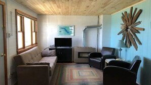 A cozy living room with a sofa, chairs, a television, and a fireplace. - Presque Isle Resort, cottage #3 of 3 (Alpena)