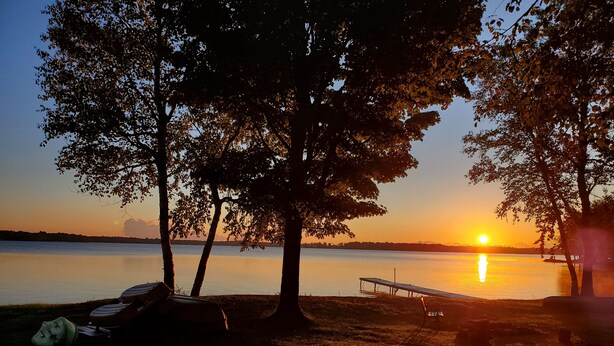 A lakeside view with trees and a dock. - Presque Isle Resort, cottage #3 of 3 (Alpena)