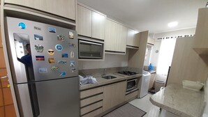 A modern kitchen with stainless steel appliances, wooden cabinets, and a built-in microwave. - 315, Ótimo Apartamento 3 Dormitórios Próximo a Praia (SC)