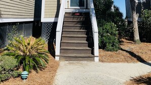 A two-story building with a central entrance, a staircase, and a palm tree.