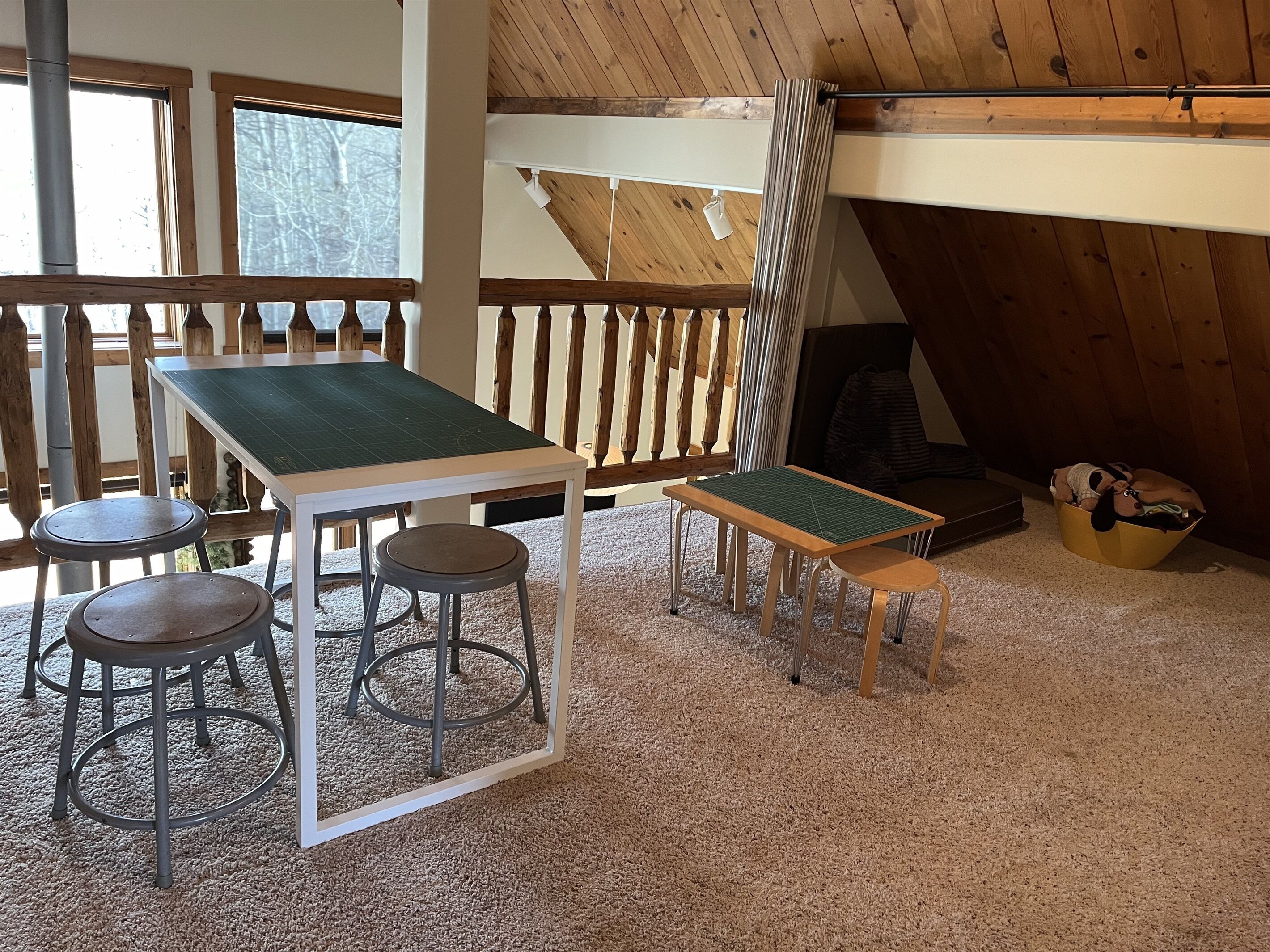 Una habitación acogedora con techo de madera, una mesa con taburetes y un ventanal con vistas a árboles.