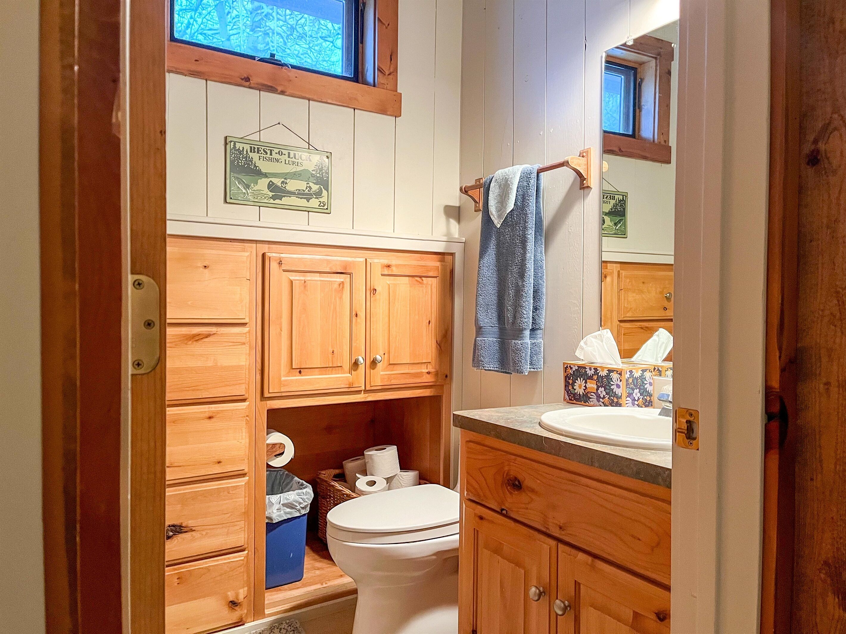 Een kleine badkamer met houten kastjes, een toilet en een wastafel.