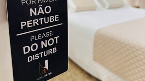 Une chambre d’hôtel avec un lit, un tableau au mur et une pancarte sur la porte.