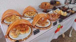Une table de buffet proposant diverses viennoiseries, notamment des petits pains, des pâtisseries et un gâteau.