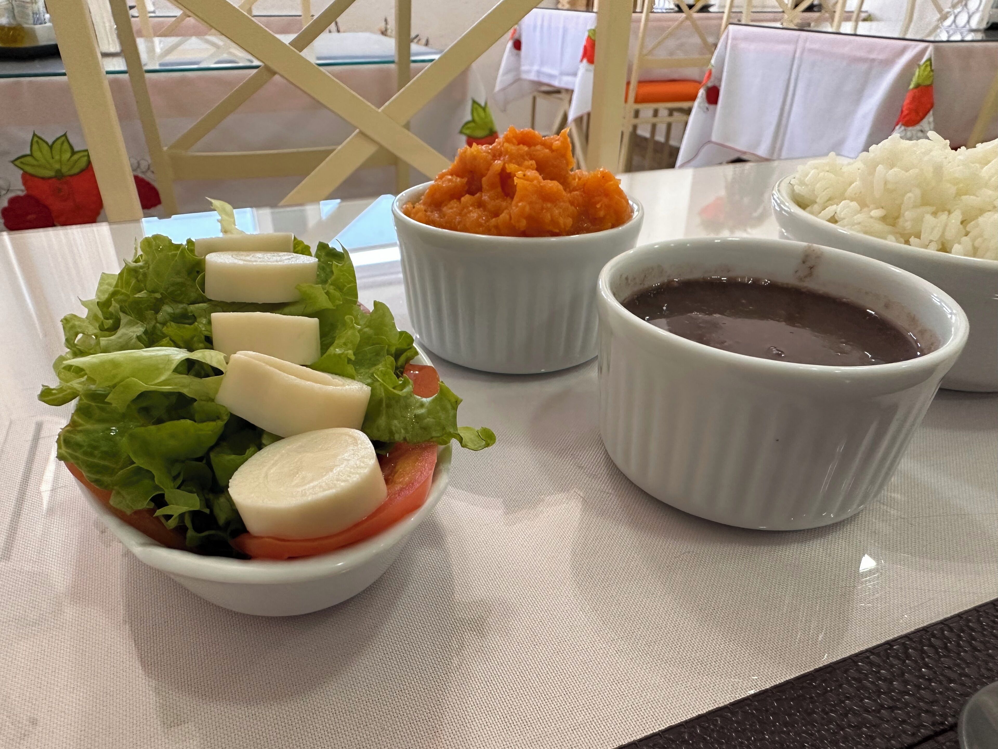 Una mesa con ensalada, un plato de arroz y un cuenco de salsa.