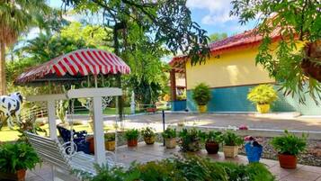 Un jardín con un columpio, plantas en macetas y un edificio de techo a ladrillo.