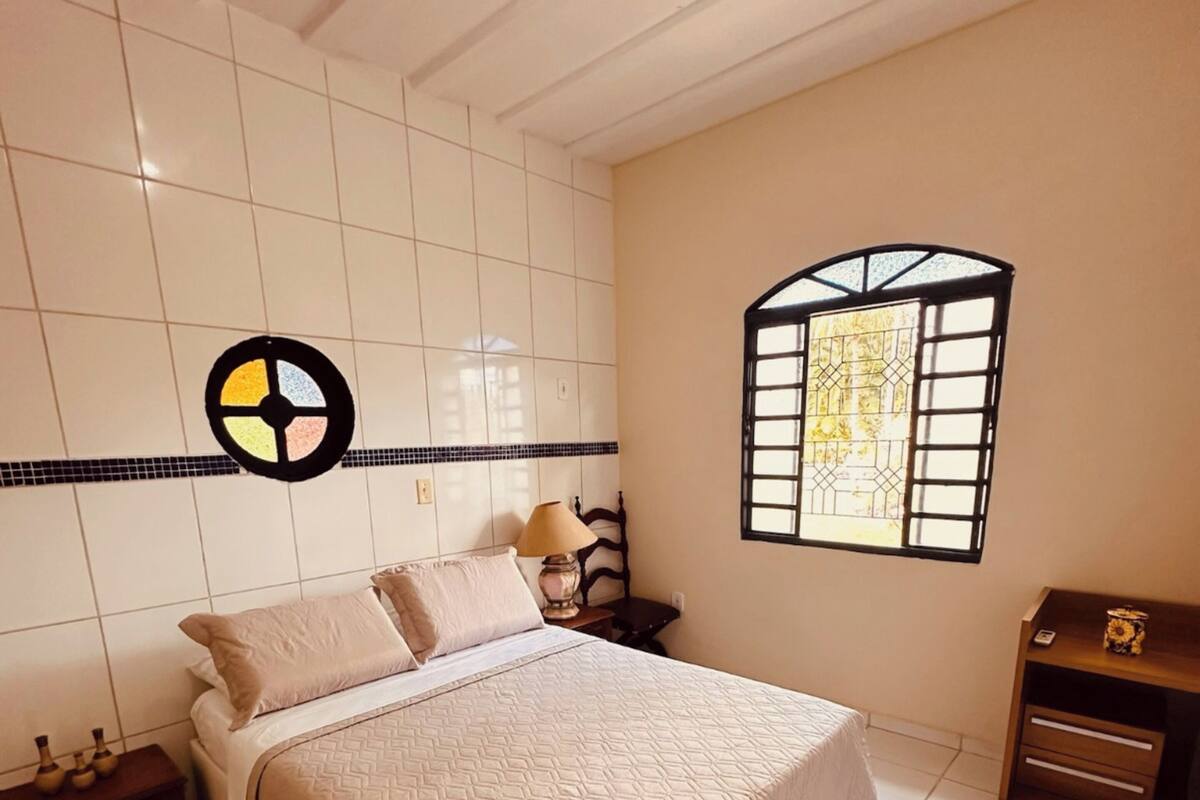 Un dormitorio con cama, mesita de noche, lámpara, cómoda, ventana y pared con un diseño circular.
