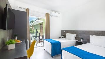 A hotel room with two beds, a desk with a TV, a chair, and a balcony with a view.