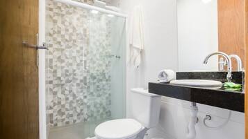 Un baño moderno con cabina de ducha de vidrio, inodoro blanco y lavamanos con encimera negra y espejo.