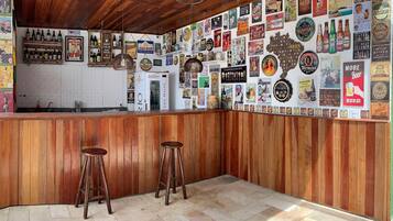 Zona de bar amb panells de fusta, dues banquettes i una paret decorada amb diferents cartells i anuncis de cervesa.
