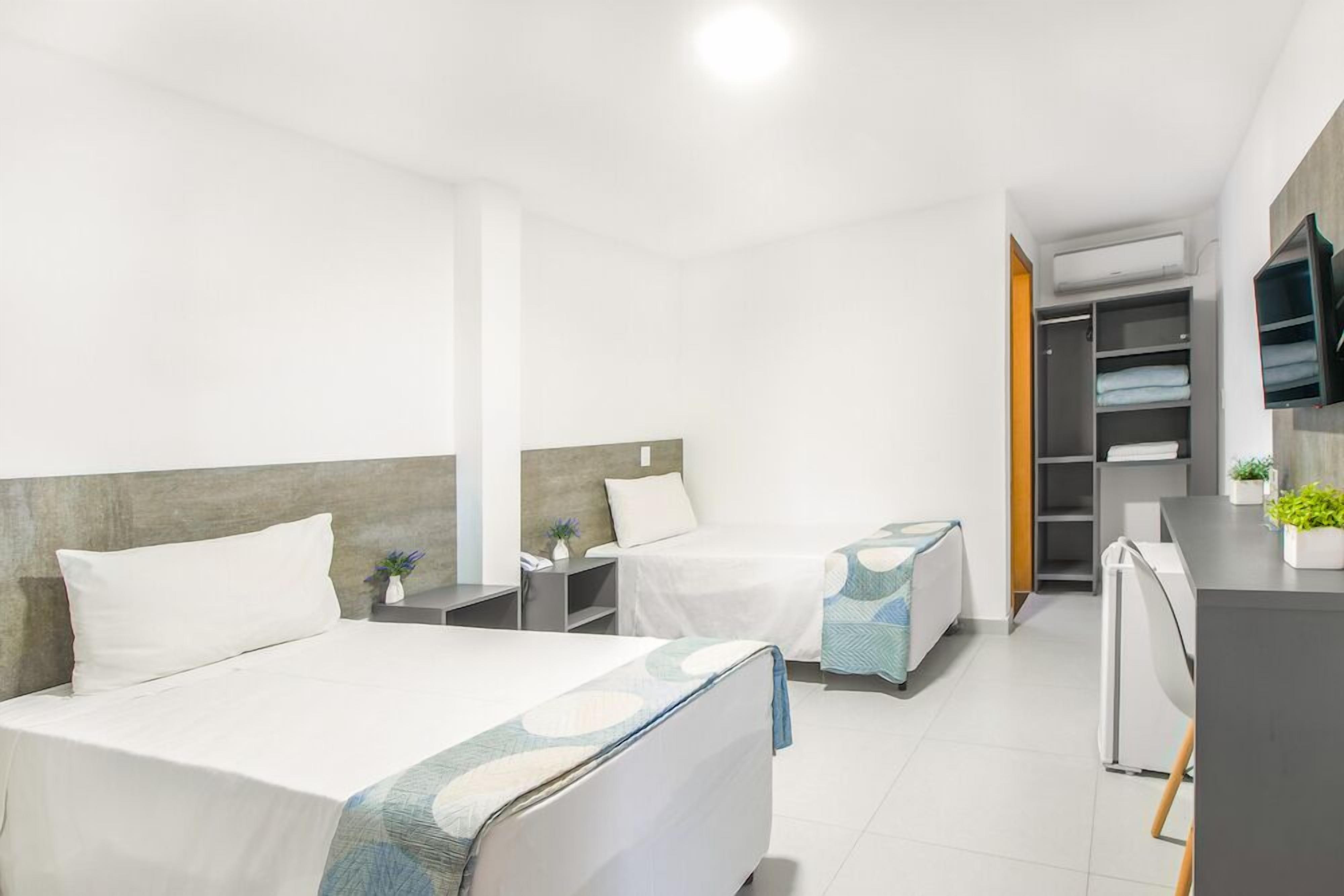 A hotel room with a large bed, a smaller bed, a desk, and a wardrobe.