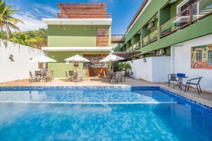 Un hotel moderno con piscina, mobiliario exterior y una decoración en tonos verde y blanco.