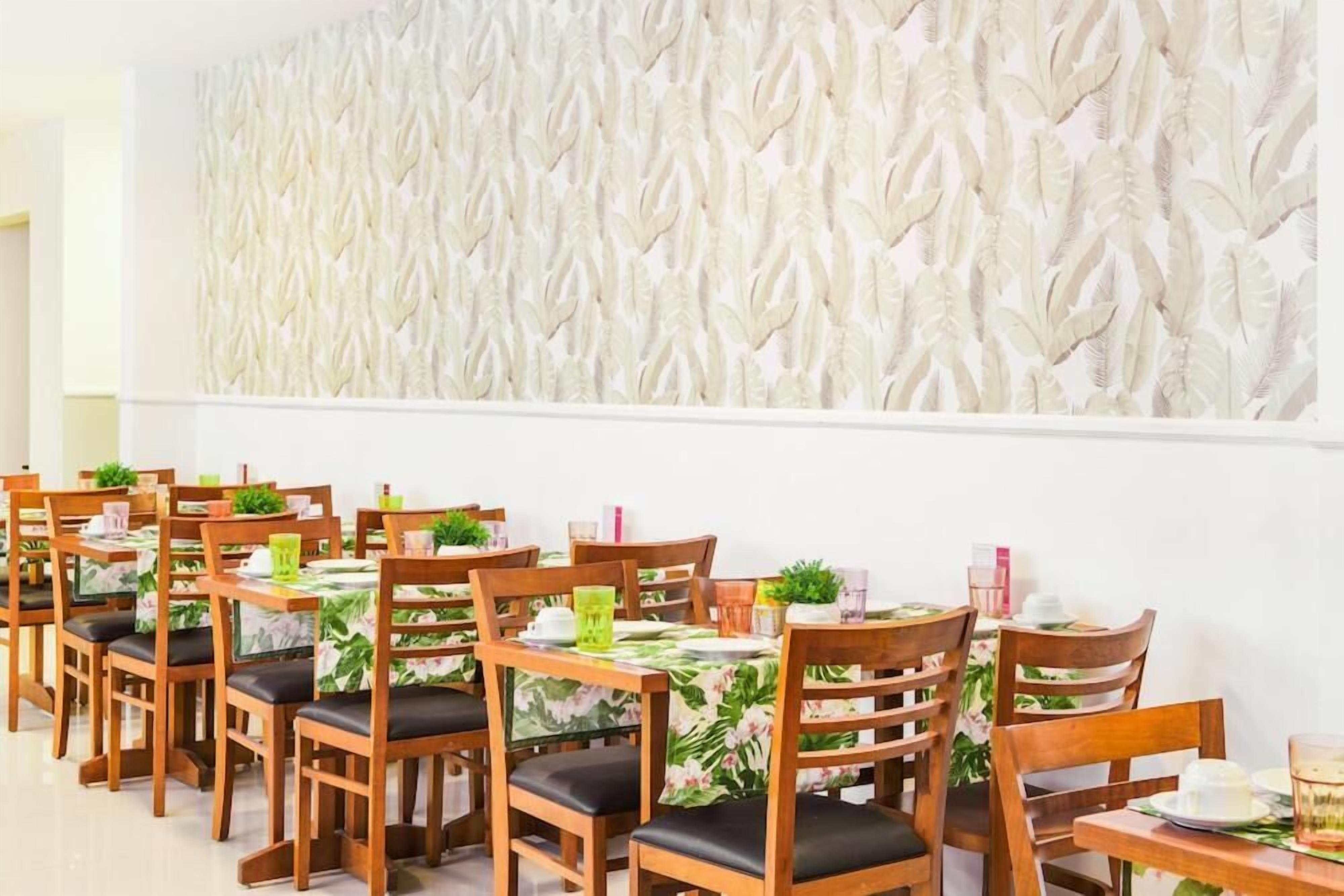 A dining area with wooden tables and chairs, each with a floral tablecloth.
