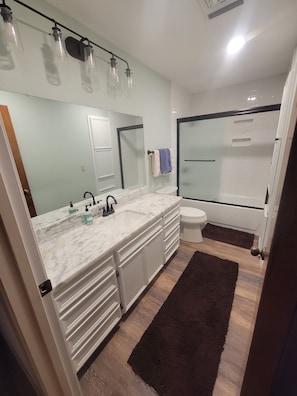 Ein modernes Badezimmer mit Marmorplatte, Duschkabine aus Glas und weißer Toilette.