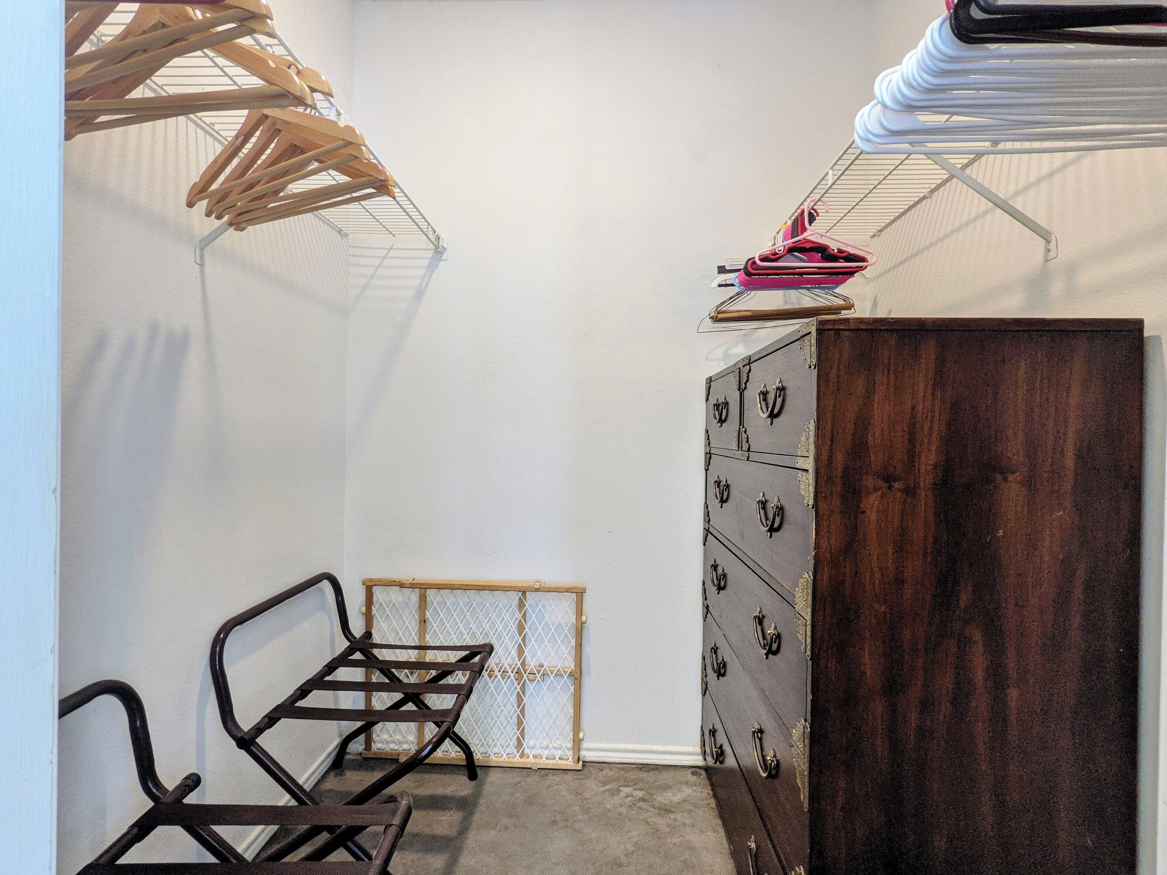 A room with a wooden dresser, a metal rack, and a metal shelf.