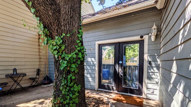 A tree with ivy growing on it, a door with a glass panel, and a satellite dish on the roof. - Modern Eco-Friendly Townhouse; Walk to Park & Recreation King Bed (Irving)