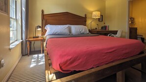 A bedroom with a wooden bed, a nightstand, a lamp, and a window with curtains. - Modern Eco-Friendly Townhouse; Walk to Park & Recreation King Bed (Irving)